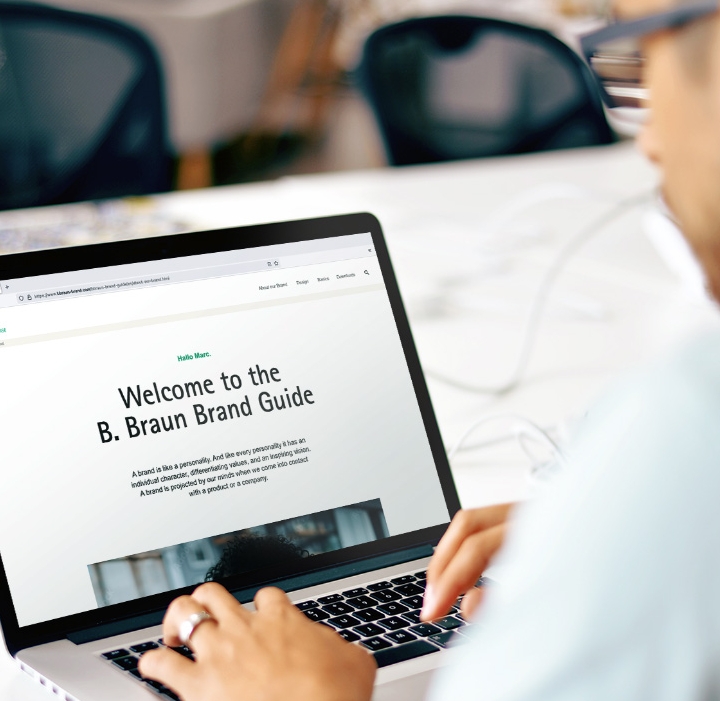 En mand i lyseblå skjorte betjener en bærbar computer med B. Brauns hjemmeside åben.