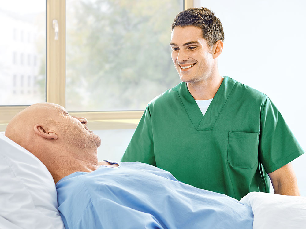 sygeplejerske og patient taler ved sengekanten