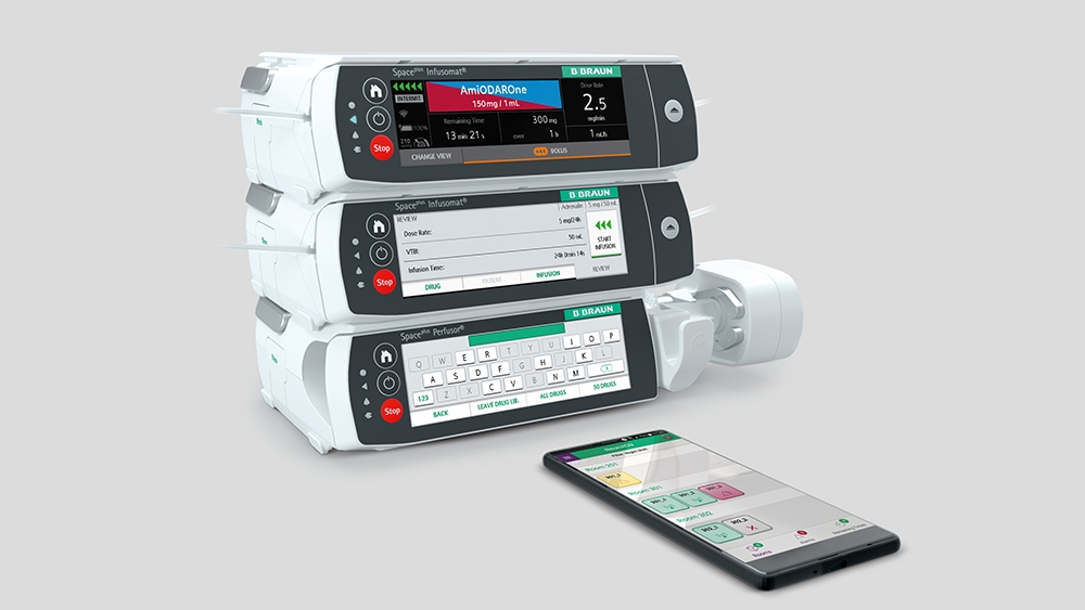 Space Plus Infusion System og en smartphone, der ligger foran det med den tilhørende app åben. 