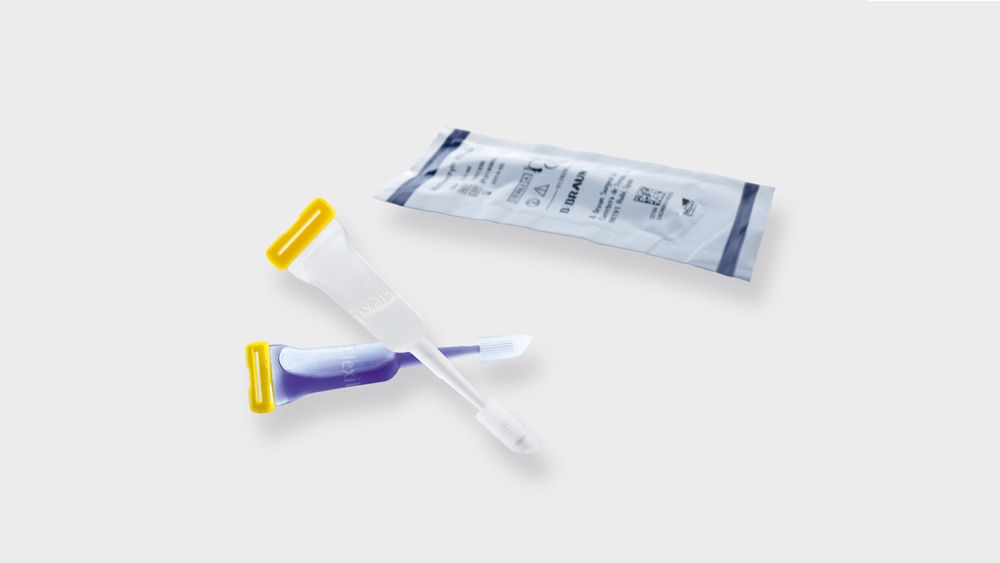 Sterile medicinske prøvetagningspinde med gule hætter og en forseglet pose, isoleret på en lys baggrund.