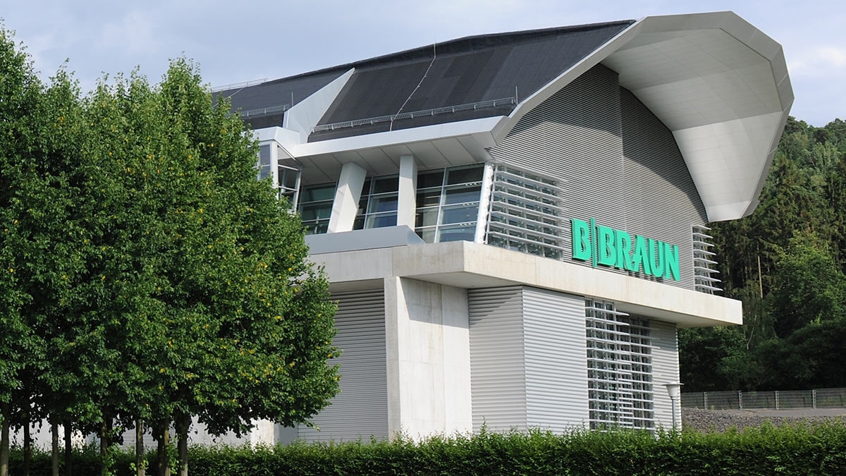 B. Braun besøgscenterbygning med et stort B. Braun-logo, der udstråler en følelse af gæstfrihed og åbenhed over for alle, der nærmer sig. 