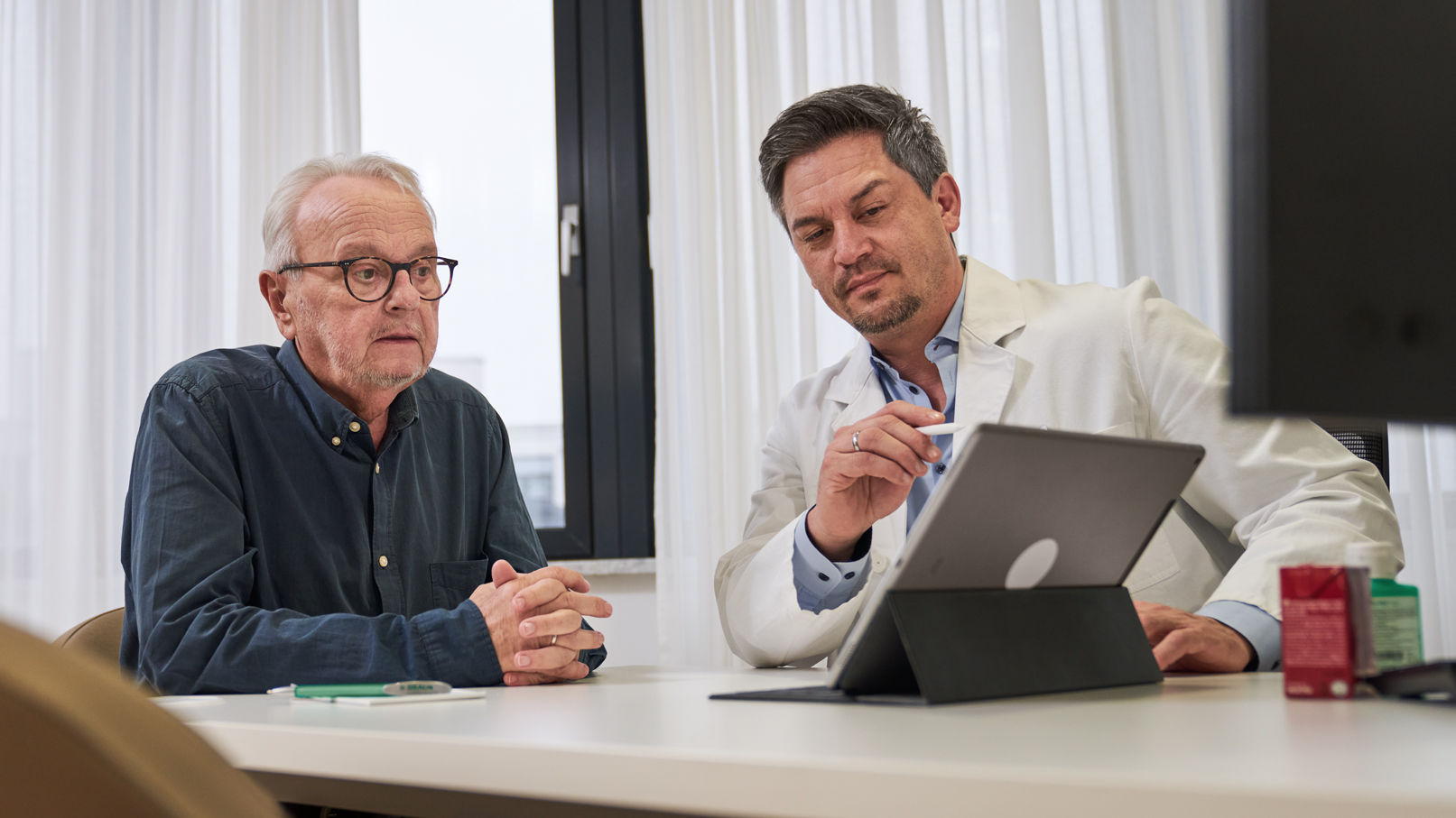 Onkolog, der konsulterer kræftpatienten og giver råd via iPad 