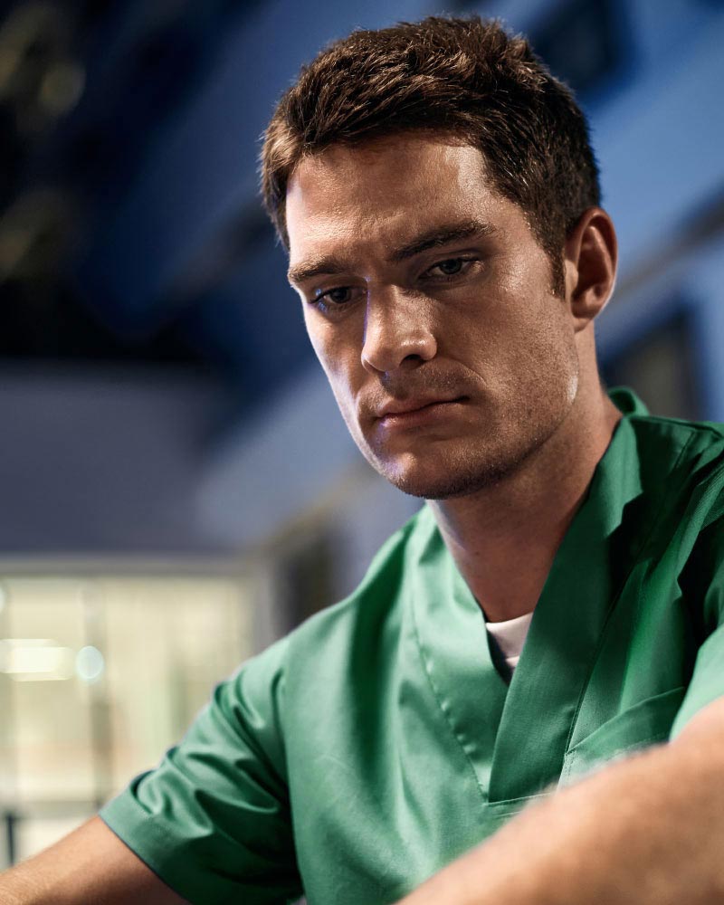 Udmattet sygeplejerske sidder foran et hospital