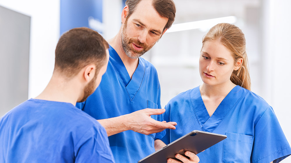 Tre læger diskuterer noget på en tablet