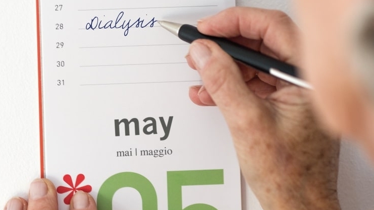 En hånd skriver dialyse i en kalender for 28. maj med en kuglepen